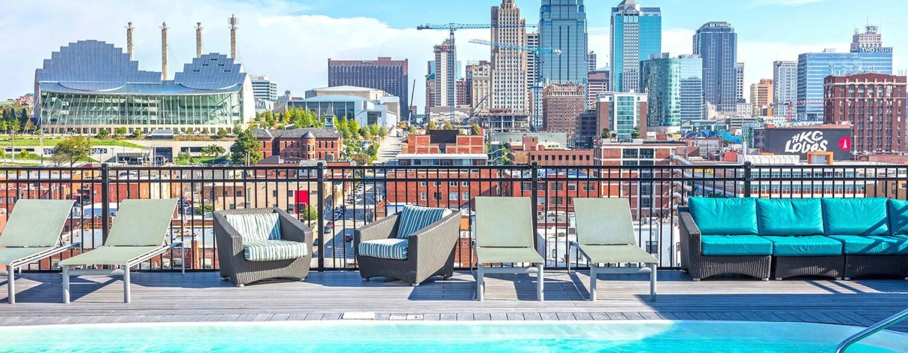 a pool with chairs and a city skyline in the background