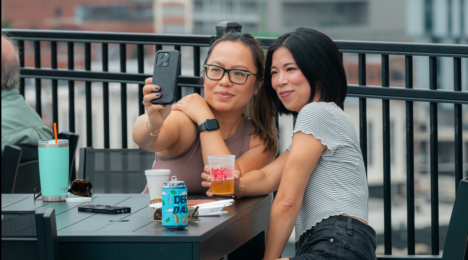 two girls sitting on the rooftop taking a selfie