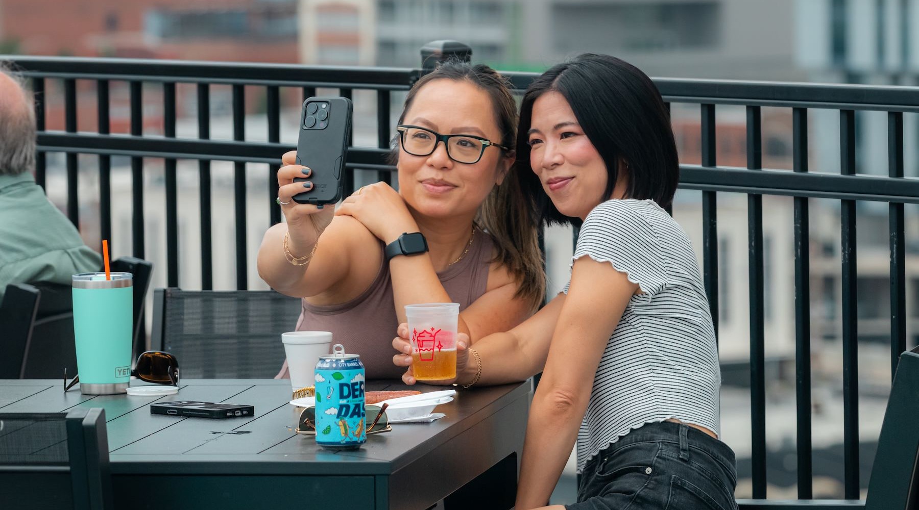 two girls sitting on the rooftop taking a selfie