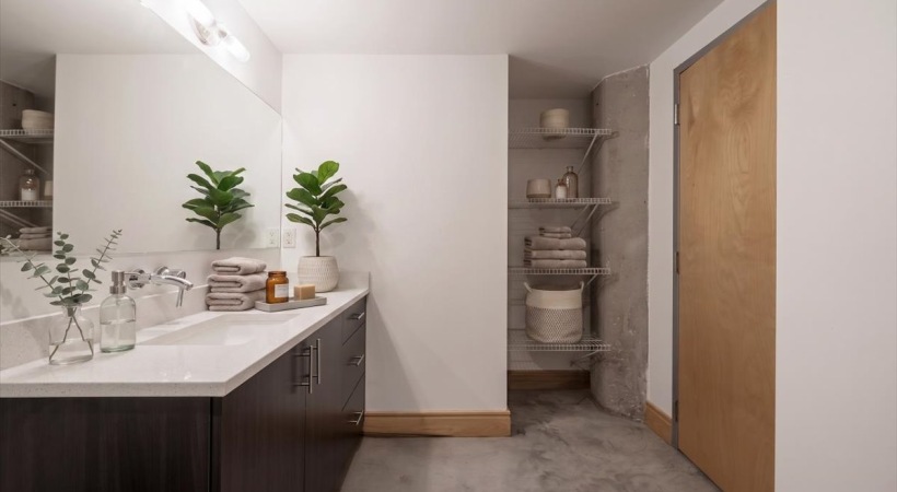 Bathroom interior with vanity, large mirror, and open shelving with towels and decor accents