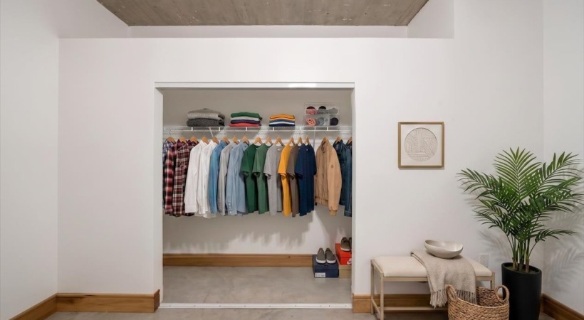 Walk-in closet at Piper Lofts with hanging storage, shelving, and neatly arranged clothing