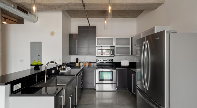 Kitchen at Piper Lofts featuring stainless steel fridge, farmhouse sink, and modern cabinetry